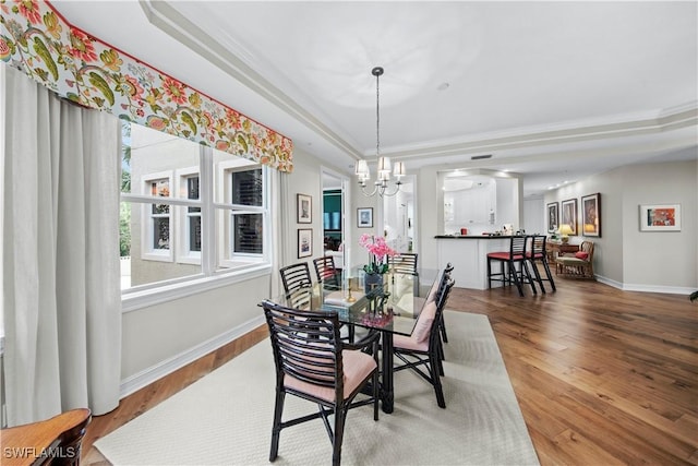 dining area with hardwood / wood-style floors, a tray ceiling, and crown molding