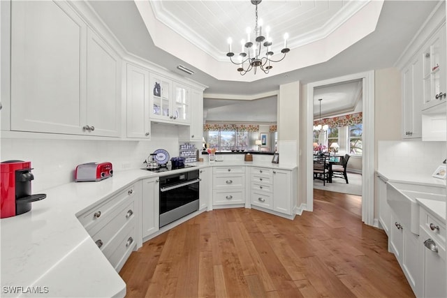 kitchen featuring pendant lighting, white cabinets, a notable chandelier, and stainless steel oven