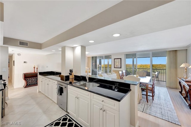 kitchen featuring sink, a center island, light tile patterned floors, dishwasher, and white cabinets