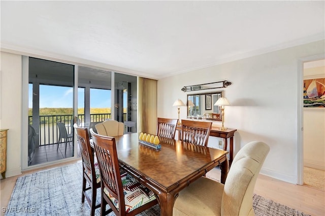 dining area featuring crown molding, a wall of windows, and light hardwood / wood-style floors