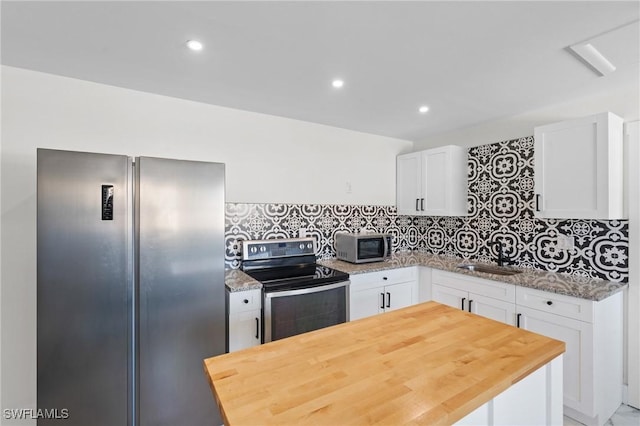 kitchen featuring tasteful backsplash, a kitchen island, stainless steel appliances, white cabinetry, and a sink