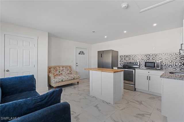 kitchen featuring butcher block countertops, open floor plan, marble finish floor, and stainless steel appliances