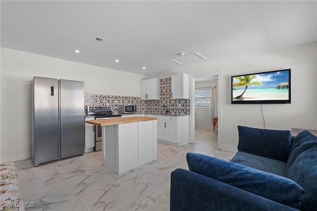 kitchen with butcher block counters, marble finish floor, appliances with stainless steel finishes, open floor plan, and a center island