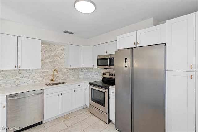 kitchen featuring visible vents, a sink, appliances with stainless steel finishes, white cabinetry, and backsplash