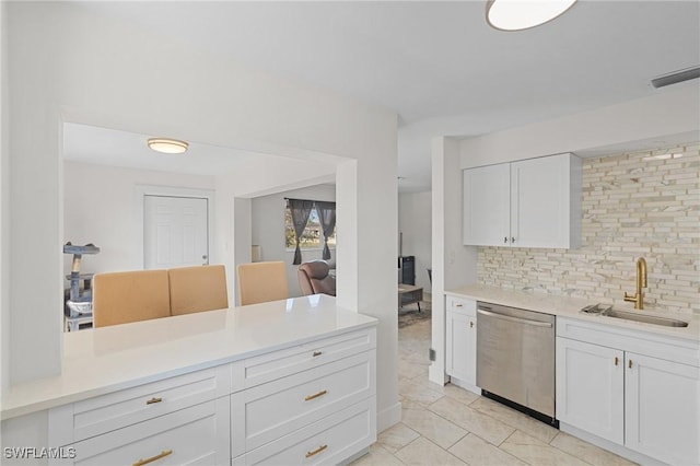 kitchen featuring stainless steel dishwasher, white cabinets, tasteful backsplash, and a sink