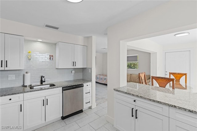 kitchen with a sink, backsplash, stainless steel dishwasher, and white cabinets