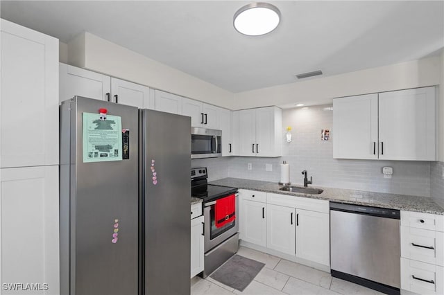 kitchen with light stone counters, visible vents, a sink, decorative backsplash, and stainless steel appliances