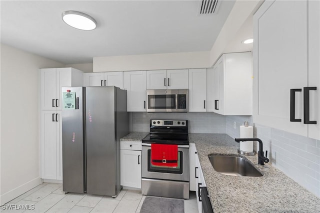 kitchen with visible vents, light stone countertops, appliances with stainless steel finishes, white cabinets, and a sink