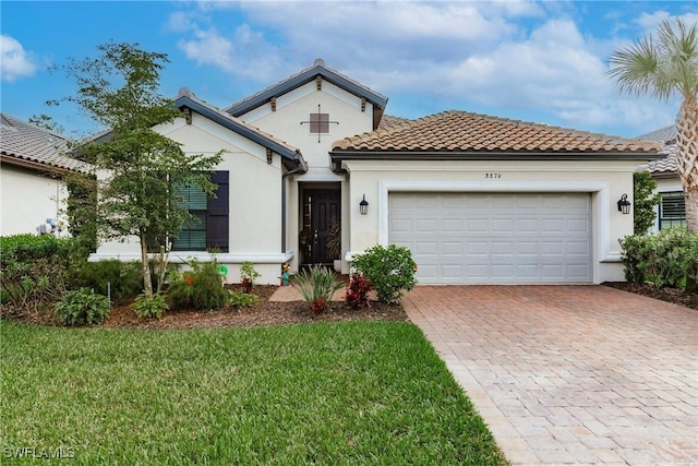 mediterranean / spanish-style house with a front lawn, decorative driveway, a garage, and stucco siding