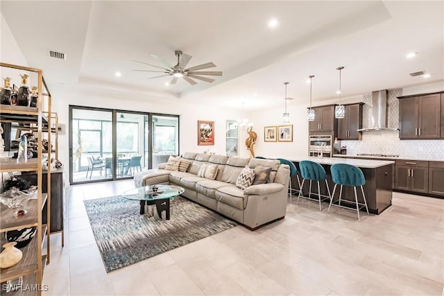 living area featuring a ceiling fan, a raised ceiling, recessed lighting, and visible vents