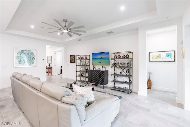living room featuring recessed lighting, baseboards, a raised ceiling, light tile patterned flooring, and a ceiling fan