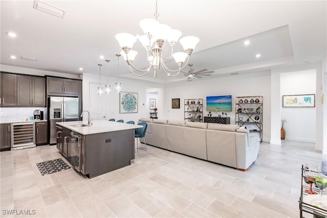 kitchen featuring light countertops, a tray ceiling, stainless steel appliances, wine cooler, and a sink