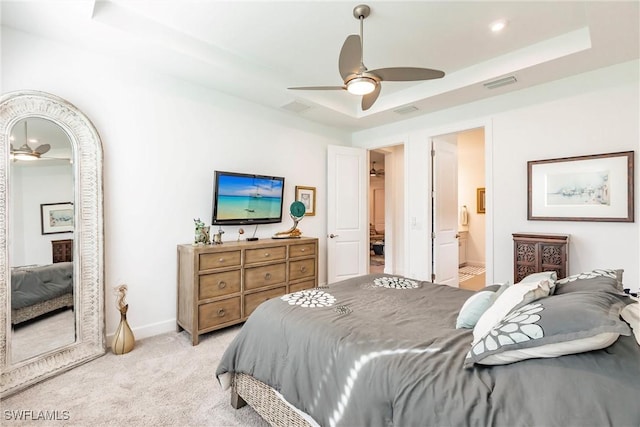 bedroom with baseboards, a tray ceiling, visible vents, and light carpet