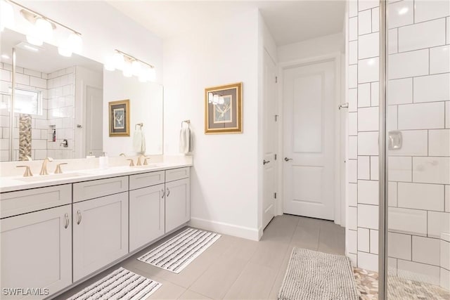 bathroom featuring tiled shower, a sink, tile patterned flooring, baseboards, and double vanity