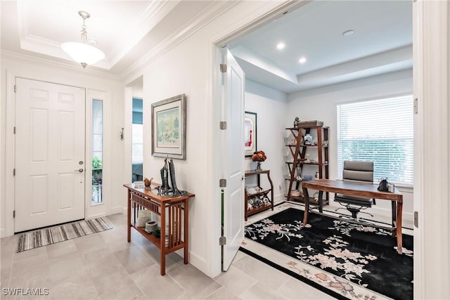 foyer featuring a tray ceiling, baseboards, and ornamental molding