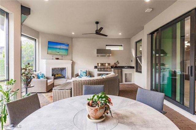 interior space featuring area for grilling, outdoor dining area, an outdoor living space with a fireplace, and ceiling fan