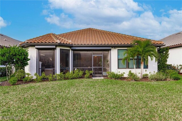 rear view of property featuring stucco siding, a tile roof, a sunroom, and a yard
