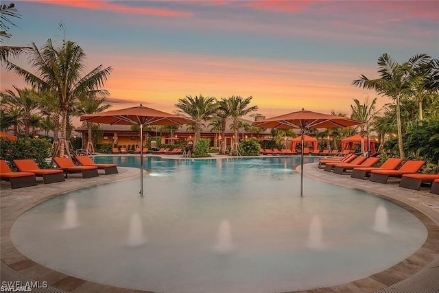 pool at dusk with a patio and a community pool