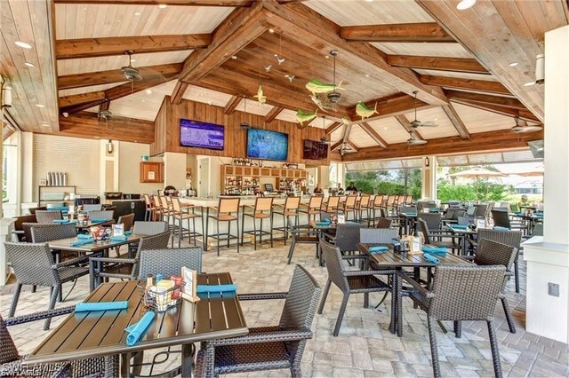 dining room with wooden walls, high vaulted ceiling, beam ceiling, and wood ceiling