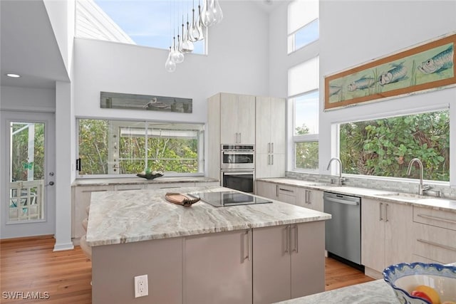 kitchen featuring light stone counters, appliances with stainless steel finishes, a center island, and hanging light fixtures