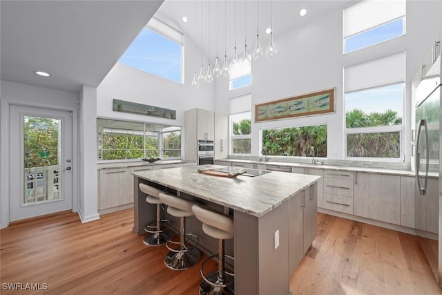 kitchen featuring light hardwood / wood-style flooring, hanging light fixtures, a kitchen breakfast bar, a center island, and a high ceiling