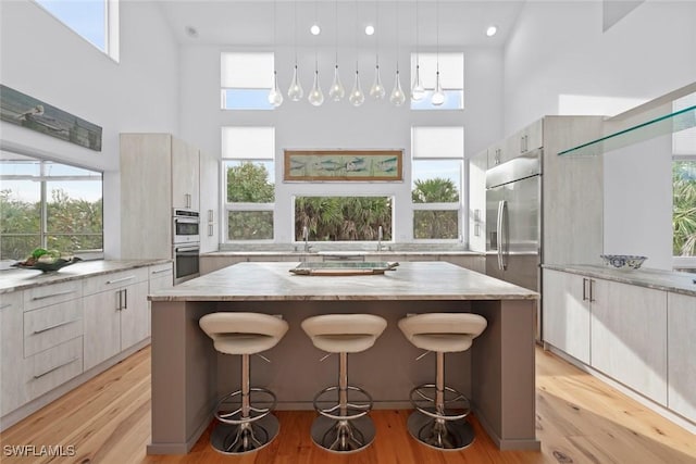 kitchen with appliances with stainless steel finishes, a towering ceiling, a kitchen breakfast bar, a center island, and decorative light fixtures