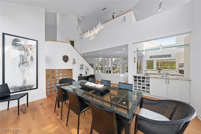 dining area featuring a towering ceiling and light hardwood / wood-style flooring