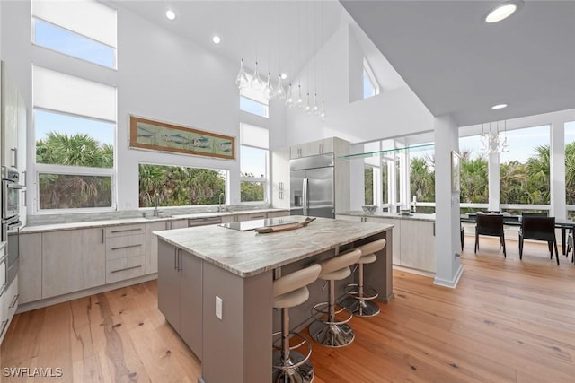 kitchen with built in refrigerator, a center island, gray cabinetry, and a kitchen bar