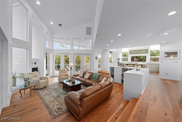 living room featuring french doors, high vaulted ceiling, and light hardwood / wood-style flooring