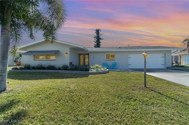 ranch-style house featuring a garage and a lawn