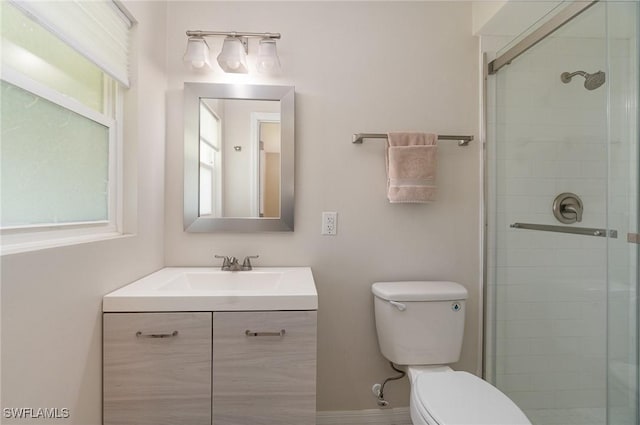 bathroom with vanity, a shower with shower door, a wealth of natural light, and toilet