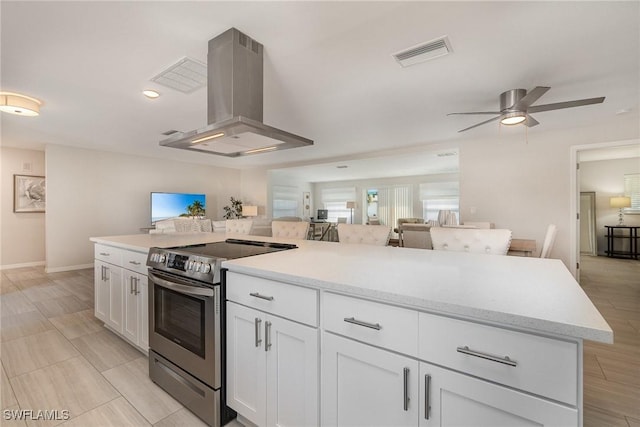 kitchen featuring white cabinets, stainless steel range with electric stovetop, island exhaust hood, a center island, and ceiling fan