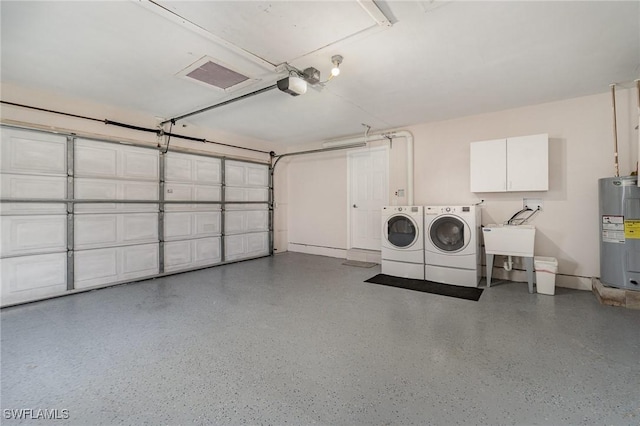 garage with a garage door opener, electric water heater, sink, and washing machine and clothes dryer