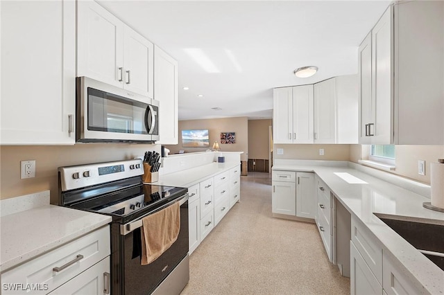 kitchen with white cabinetry, sink, light stone countertops, and appliances with stainless steel finishes