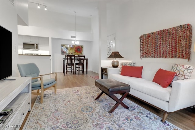 living room with a towering ceiling, a notable chandelier, and light hardwood / wood-style floors