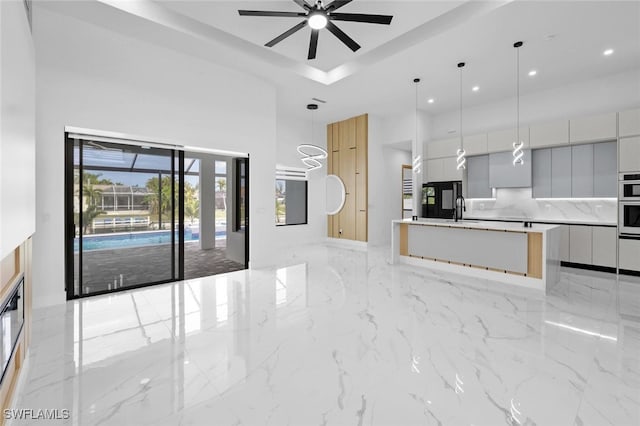 kitchen with pendant lighting, an island with sink, decorative backsplash, sink, and gray cabinetry