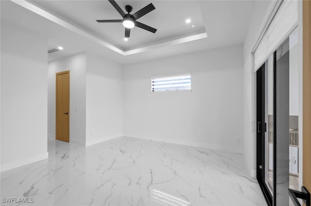 unfurnished room featuring ceiling fan and a tray ceiling