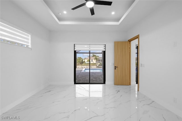 empty room featuring ceiling fan and a raised ceiling