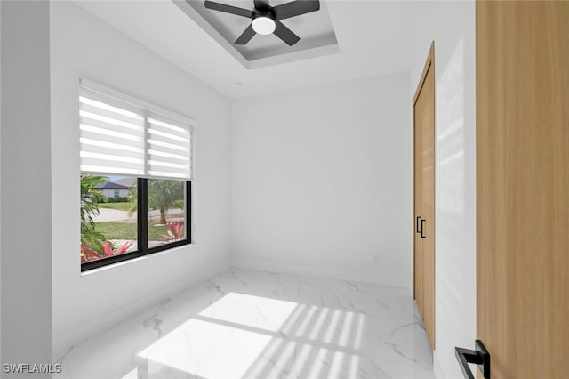 unfurnished room featuring ceiling fan, a healthy amount of sunlight, and a raised ceiling