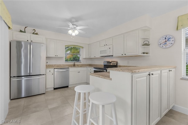 kitchen with white cabinets, stainless steel appliances, sink, kitchen peninsula, and a breakfast bar