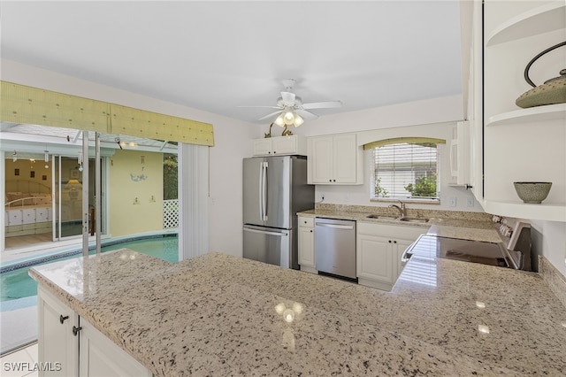 kitchen with light stone countertops, sink, white cabinets, and appliances with stainless steel finishes