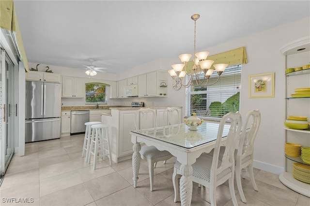 dining space with sink, ceiling fan with notable chandelier, and light tile patterned floors