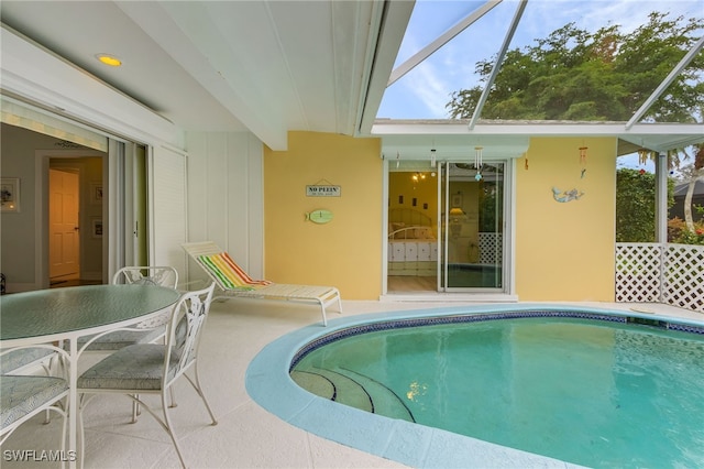 view of swimming pool with glass enclosure and a patio area