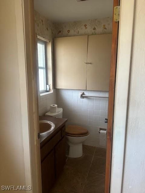 bathroom with tile walls, vanity, tile patterned floors, and toilet