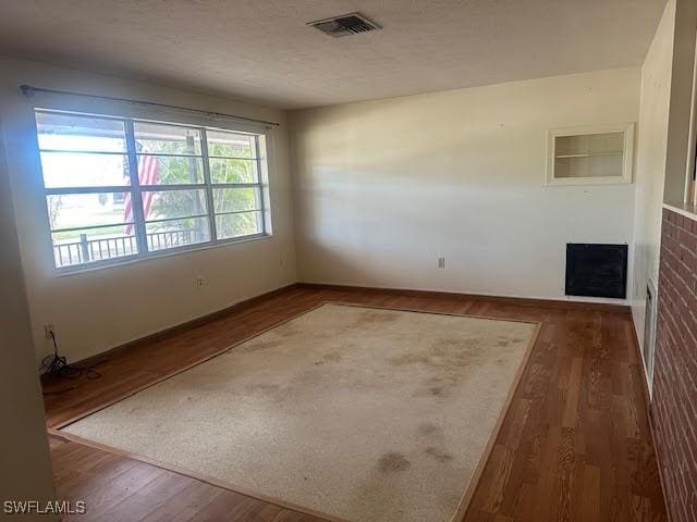 empty room with dark hardwood / wood-style flooring and a textured ceiling