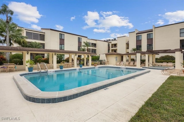 community pool with a community hot tub, a patio, and a pergola