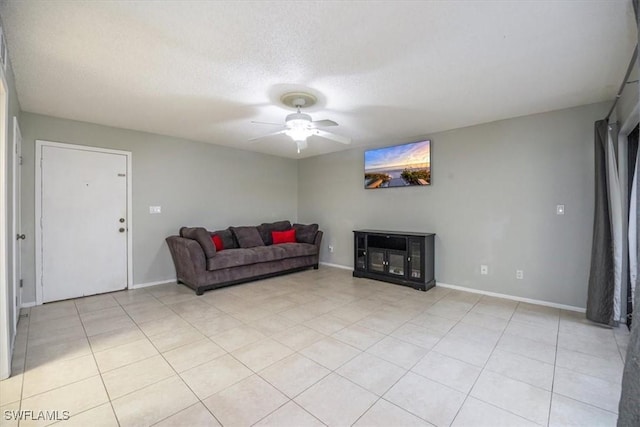 living area with light tile patterned floors, ceiling fan, baseboards, and a textured ceiling