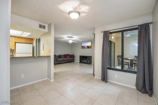 spare room with light tile patterned floors, visible vents, ceiling fan, a textured ceiling, and baseboards