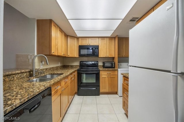 kitchen with light tile patterned floors, visible vents, a sink, dark stone counters, and black appliances