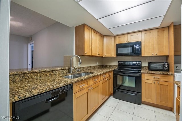 kitchen with light tile patterned floors, a toaster, a sink, dark stone counters, and black appliances